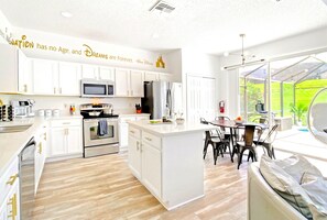A modern kitchen with white cabinetry, stainless steel appliances, and a large island.