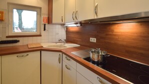 A modern kitchen with white cabinets, a wooden countertop, a sink, and a stove. - Holiday Home in Robertville Near Lake & Sauna (Waimes)