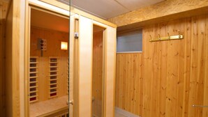 A sauna room with wooden walls and a glass door, a wooden bench, and a towel rack. - Holiday Home in Robertville Near Lake & Sauna (Waimes)
