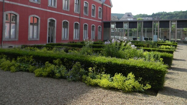 A red building with multiple windows and a garden in front. - Romantic Cottage in Ardennes (Stoumont)