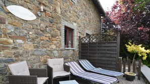 A stone building with a stone wall, a wooden fence, and a potted plant. - Romantic Cottage in Ardennes (Stoumont)