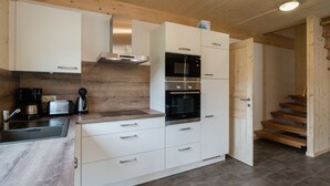 Una cucina moderna con mobili bianchi, elettrodomestici in acciaio inossidabile e soffitto in legno.
