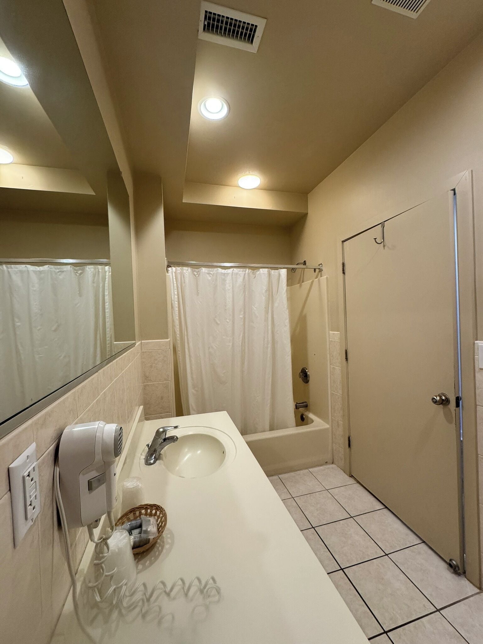Une salle de bain équipée d’un lavabo, d’un miroir, d’une douche et de toilettes.