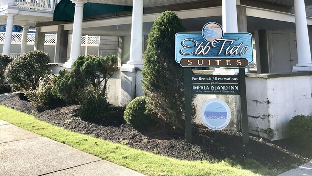 A beachfront hotel with a balcony, white columns, and a sign for 'Ebb Tide Suites'. - Ebb Tide Suites (Ocean City)