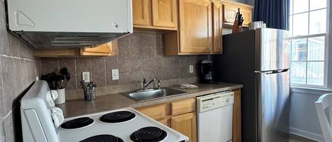 A modern kitchen with a stove, sink, dishwasher, and refrigerator.