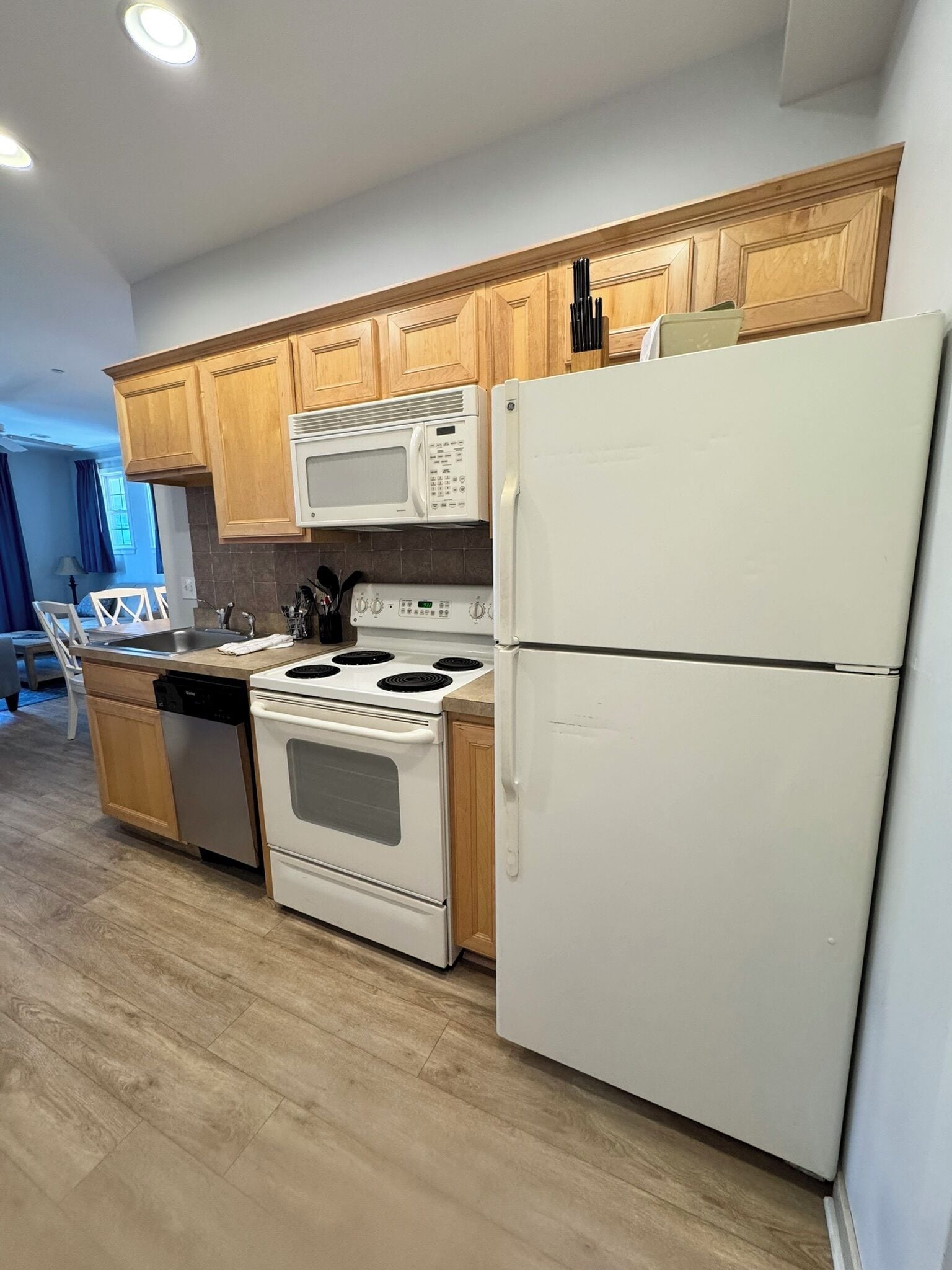 A kitchen with wooden cabinets, a white stove, a microwave, and a refrigerator.