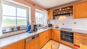 A modern kitchen with wooden cabinets, a built-in oven, a microwave, and a coffee maker.