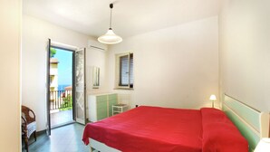 A bedroom with a bed, a nightstand, a lamp, a dresser, and a window. - Belvilla by OYO Comfortable Apartment With Pool (Cerignola)