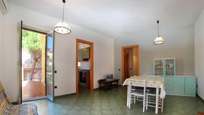 A spacious living area with a sofa, a dining table, and a kitchen visible through an open door. - Belvilla by OYO Comfortable Apartment With Pool (Cerignola)