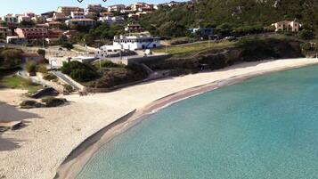 Un hotel sulla costa con vista sulla spiaggia, posizionato su un pendio con edifici sullo sfondo.