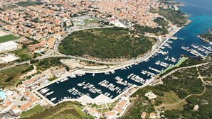An aerial view of a coastal town with a marina, residential areas, and a prominent hill. - Belvilla by OYO Comfortable Apartment With Pool (Cerignola)