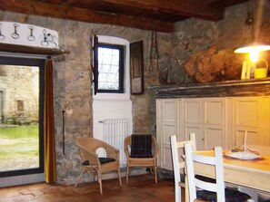 A rustic room with stone walls, a wooden ceiling, a table with chairs, a window, and a radiator. - Tuscan Hideaway With Pool (San Godenzo)