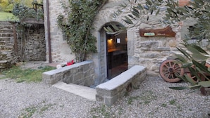 Un bâtiment en pierre avec une porte en bois, un banc en pierre et une pancarte indiquant « Alia Via dei Parchi ».
