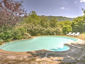A swimming pool with a curved edge, surrounded by a stone deck and lush greenery. - Tuscan Hideaway With Pool (San Godenzo)