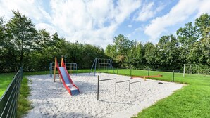 A playground with a slide, climbing structures, and a fenced area. - Peaceful Holiday Home (Anjum)