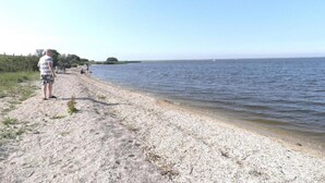 A pebbled beach with a person standing by the water's edge. - Peaceful Holiday Home (Anjum)