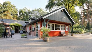 A rustic building with a red facade, large windows, and a covered porch.