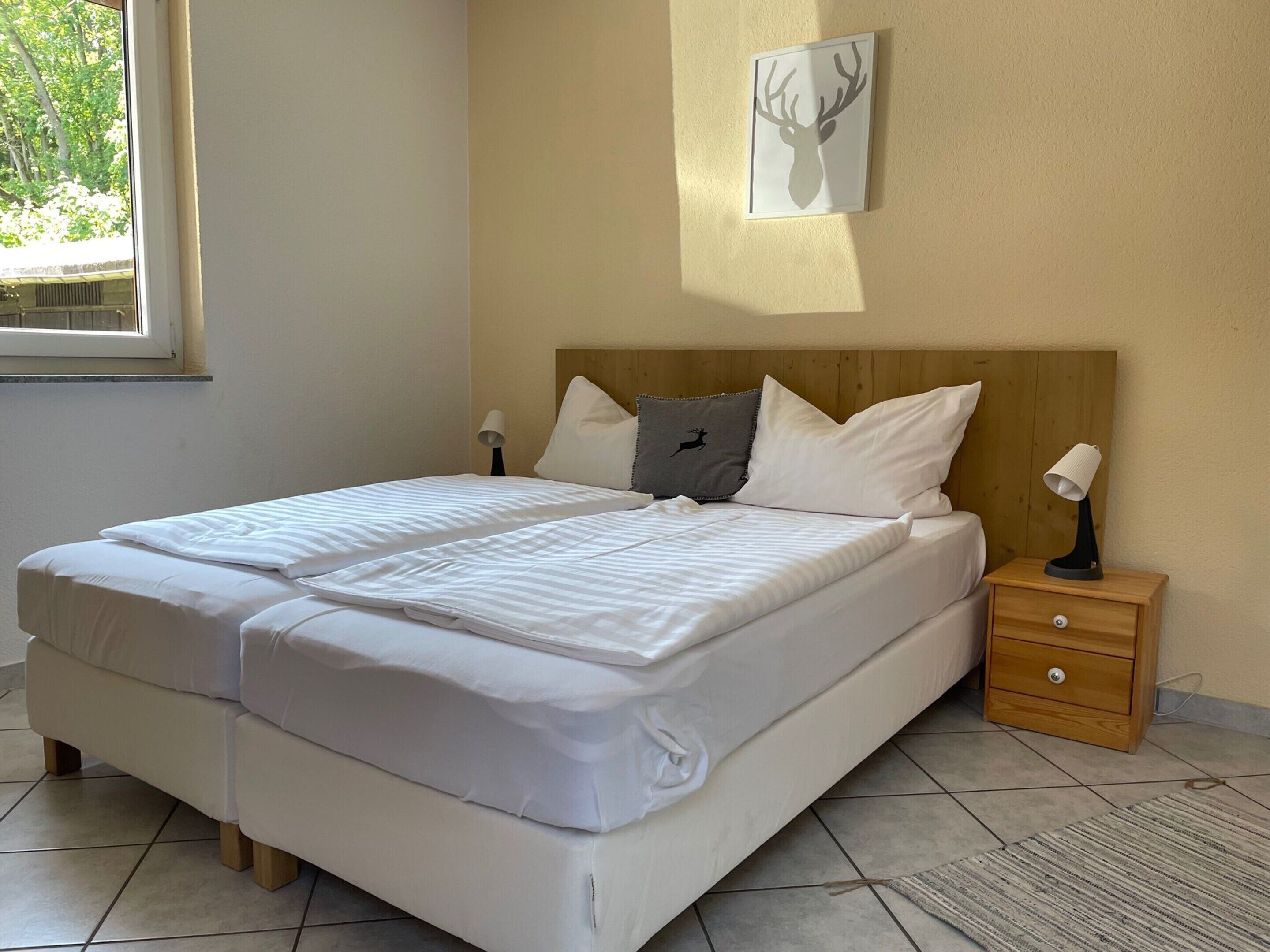 A neatly made bed with white linens, a wooden headboard, and a small bedside table with a lamp.