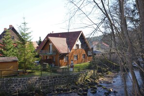 Ein Holzhaus mit geneigtem Dach, einer Steinmauer und einem kleinen Garten.