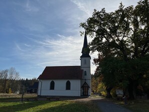 Situated in a rural setting, this traditional church features a prominent steeple and a white facade.