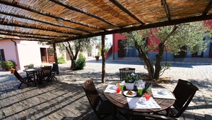 An outdoor patio with a round table, chairs, and a covered area. - Farmhouse Montalto Near Sandy Beaches (Montalto di Castro)
