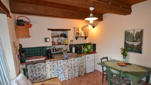 Une cuisine compacte avec un plafond en bois, un petit évier et un coin repas comprenant une table et des chaises.