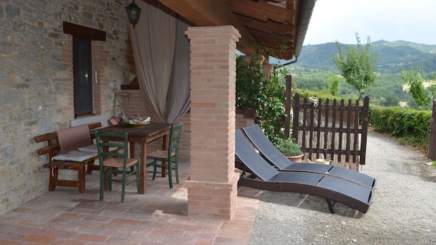 Un bâtiment en pierre doté d’un patio couvert, d’une table avec des chaises et d’une vue sur la campagne.