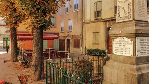 A street scene with outdoor seating, a plaque, and a building with a sign.