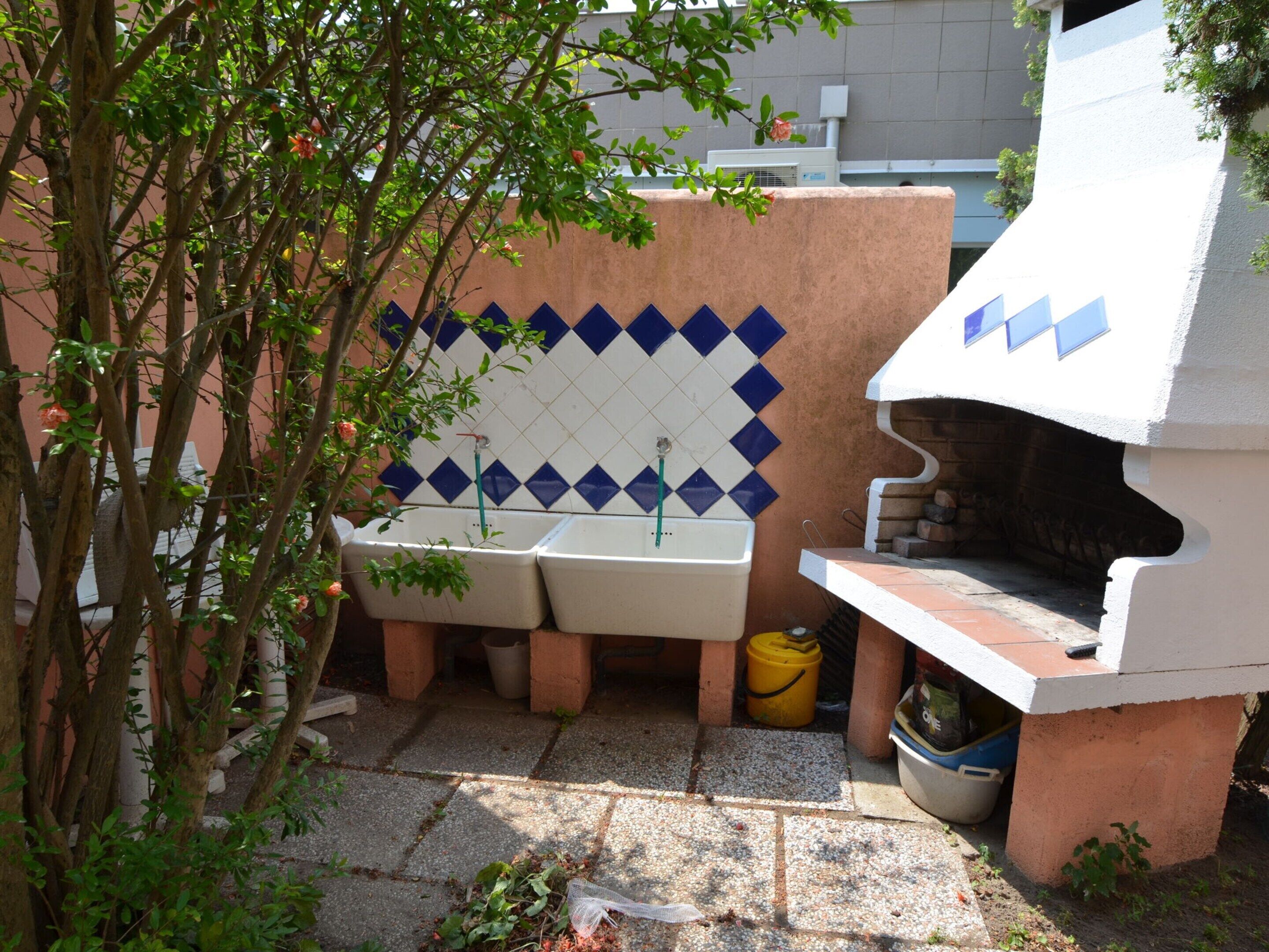 Una zona de cocina con una parrilla empotrada, dos lavabos y un salpicadero de azulejos.