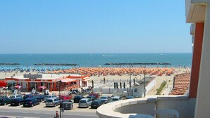 A beachside view with a parking lot, beach umbrellas, and a bar named "Ragno Bar Astor". - Belvilla by OYO Porto Garibaldi Bilo Doria (Comacchio)