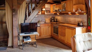A rustic kitchen with wooden cabinets, a built-in oven, and a television on a small table. - Heritage Holiday Home in Wienhausen near River (Wienhausen)