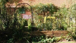 Ein Garten mit Backsteinmauer, Holzzaun und verschiedenen Pflanzen.