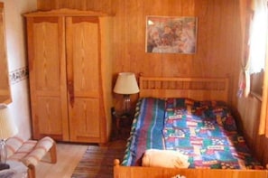 Ein Schlafzimmer aus Holz mit Bett, Kleiderschrank, Lampe und einem Bild an der Wand.