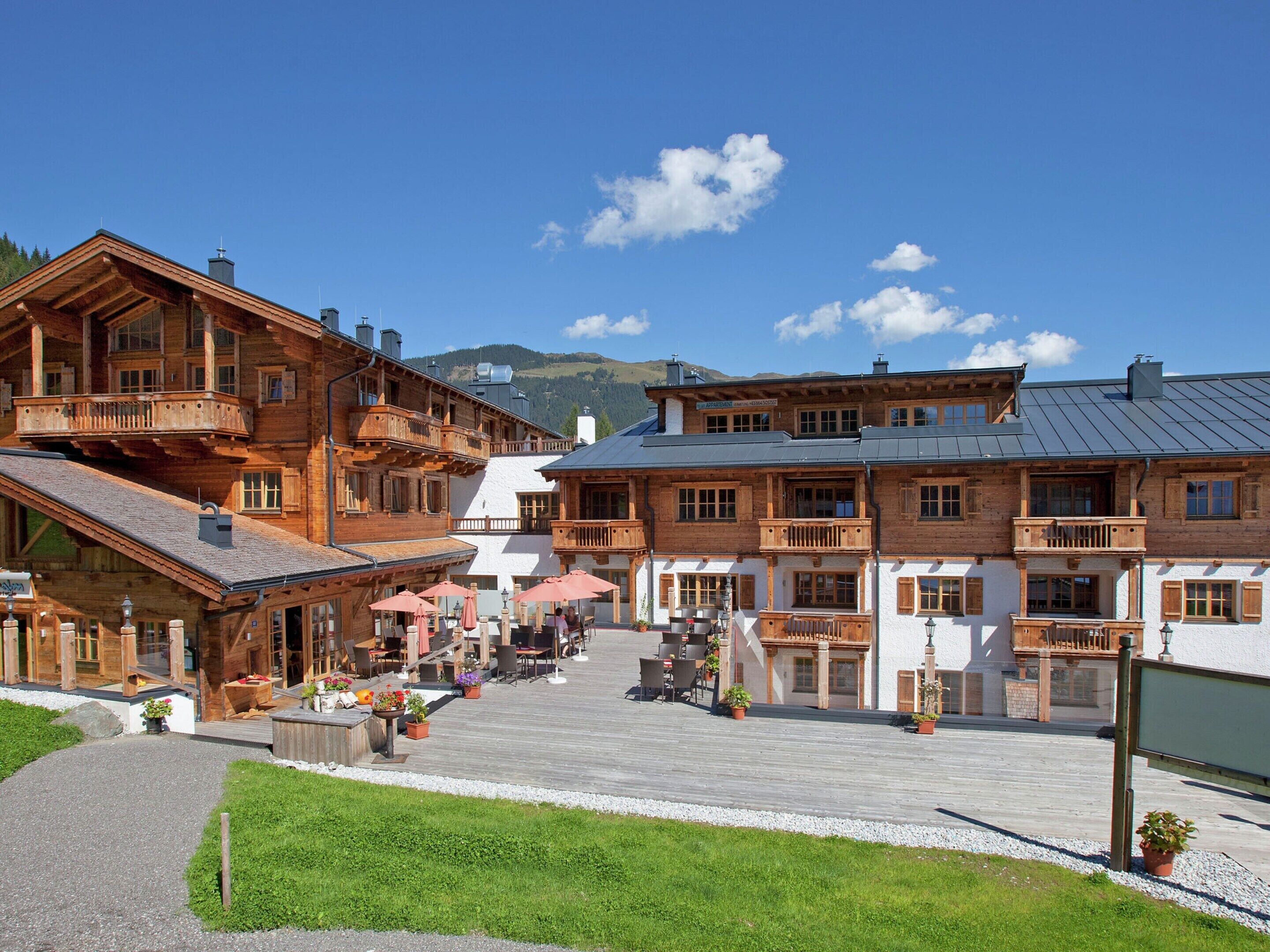 A traditional wooden building with balconies, a paved courtyard, and outdoor seating.