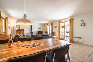A dining area with a wooden table, chairs, a bottle of wine, and glasses. - Modern Villa With Heated Pool (Beaufort)