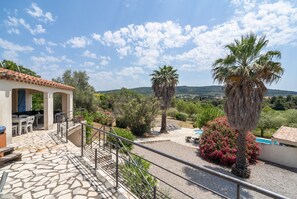 A patio with stone flooring, outdoor furniture, and a view of a pool and hills. - Modern Villa With Heated Pool (Beaufort)