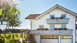 A two-story house with a garage, a swing set, and flower boxes on the balconies. - Bright Alpine Retreat (Ingenried)
