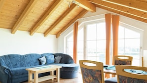 A cozy room with a wooden ceiling, a blue sofa, a small table, and chairs with patterned upholstery. - Bright Alpine Retreat (Ingenried)