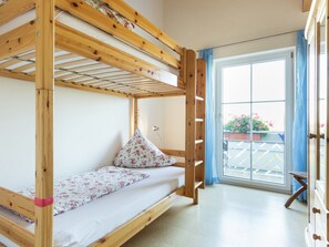 Un lit superposé avec un coussin à motifs floraux et une petite table à côté.