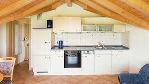 A kitchen with white cabinets, a black oven, and a tiled backsplash. - Bright Alpine Retreat (Ingenried)