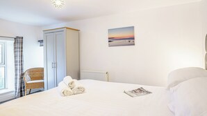 A hotel room with a large bed, a chair, a painting, and a window with curtains. - 3 bedroom accommodation in New Quay (New Quay)