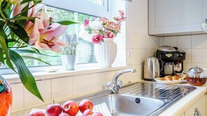 A kitchen with a stainless steel sink, a coffee maker, and a plate of apples. - 3 bedroom accommodation in New Quay (New Quay)