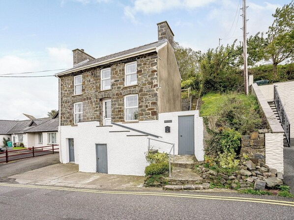 Une maison en pierre à deux étages, avec une façade blanche et une porte grise.