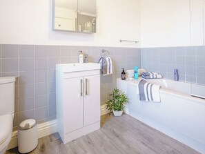 Une salle de bain moderne équipée de toilettes, d’un lavabo, d’un miroir et d’une baignoire.