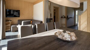 A modern interior with a dining table, chairs, a sofa, and a TV mounted on the wall. - Chalet in the ski Area in Styria (Sankt Georgen am Kreischberg)