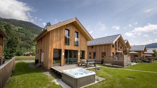 A wooden cabin with a hot tub, outdoor seating, and a view of the mountains. - Chalet in the ski Area in Styria (Sankt Georgen am Kreischberg)