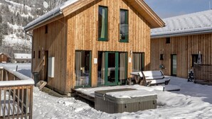 A wooden cabin with a sloped roof, large windows, and a covered outdoor seating area. - Chalet in the ski Area in Styria (Sankt Georgen am Kreischberg)