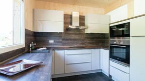 A modern kitchen with white cabinets, dark countertops, and built-in ovens. - Chalet in the ski Area in Styria (Sankt Georgen am Kreischberg)