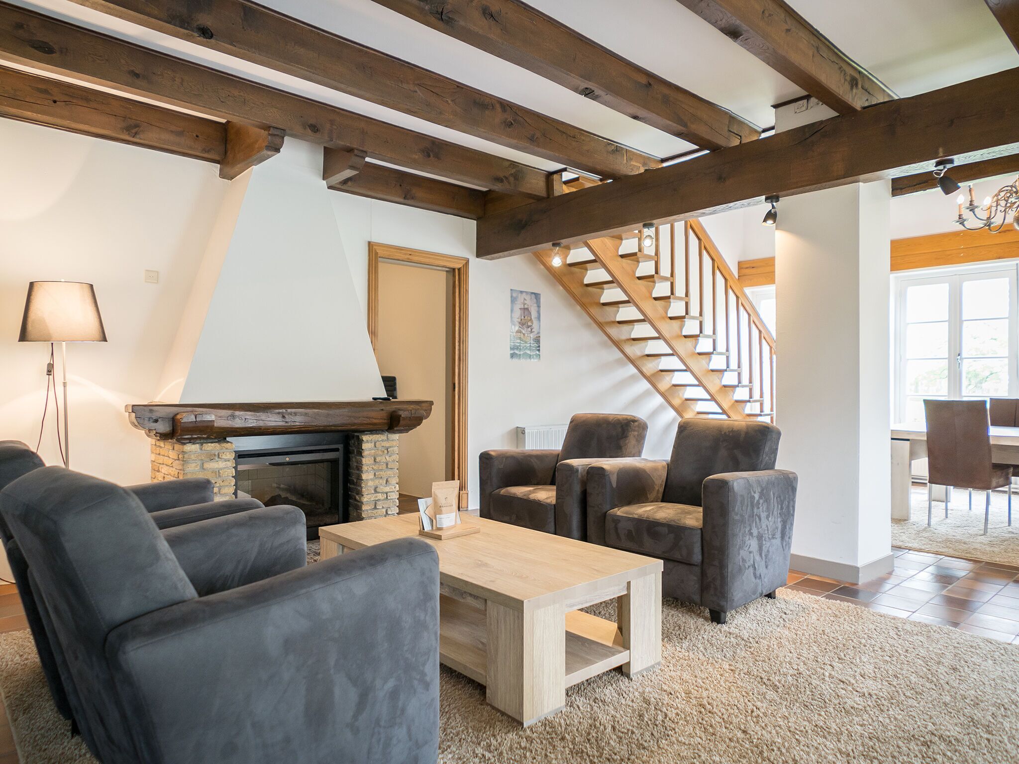 A cozy living room with a fireplace, comfortable seating, and a staircase leading to another level.