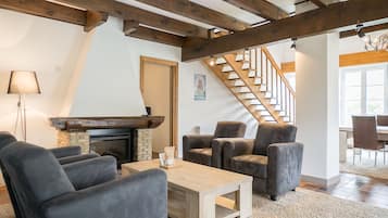 A cozy living room with a fireplace, comfortable seating, and a staircase leading to another level.